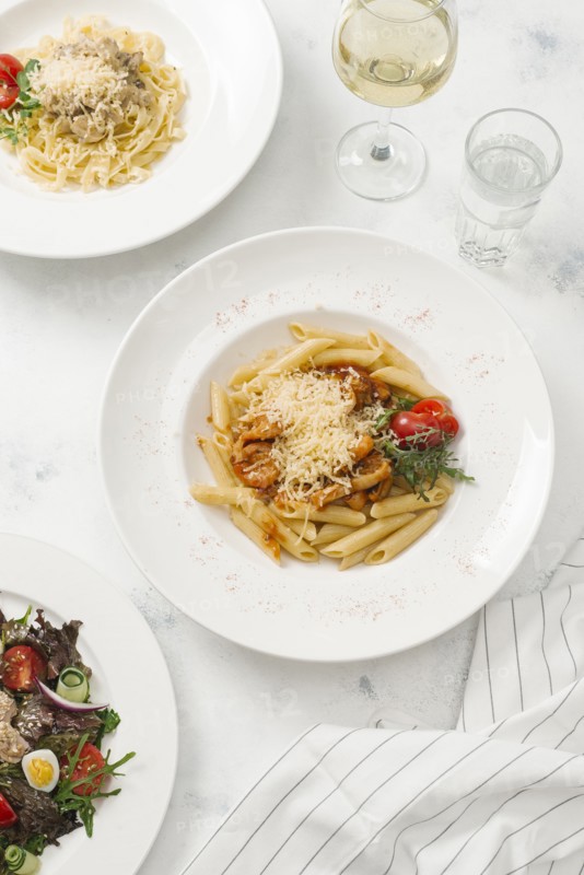 Bowl of pasta topped with cheese by white wine