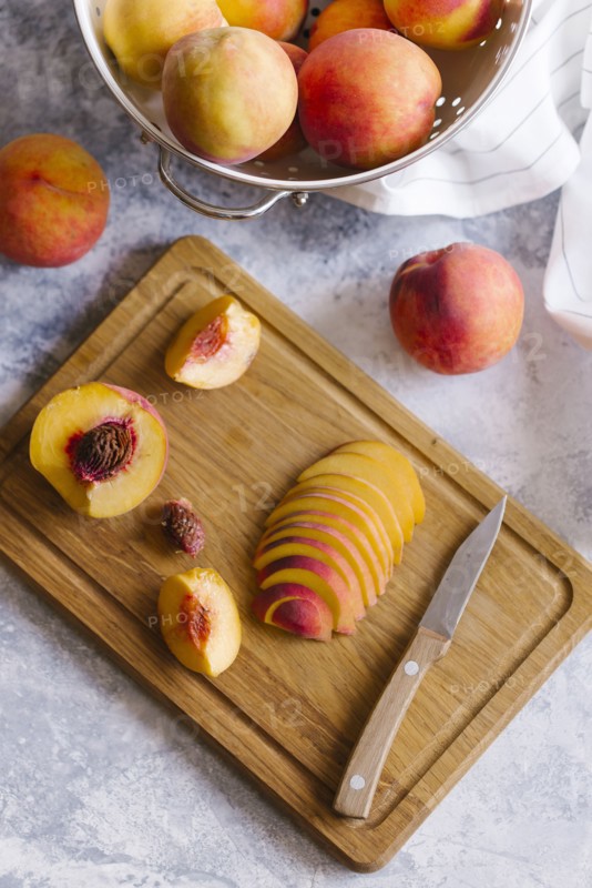 Peaches sliced on wooden cutting board
