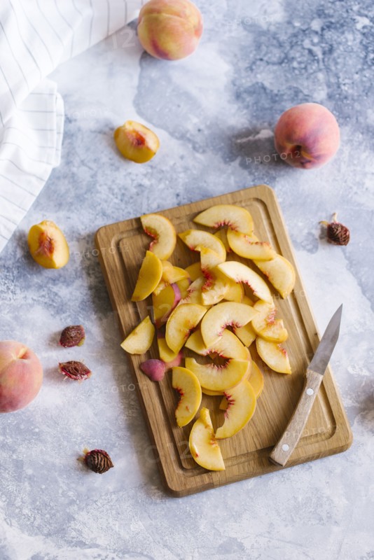 Peaches sliced on wooden cutting board