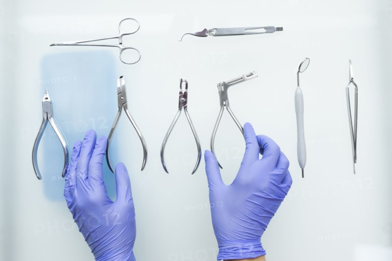 Hands of dental assistant wearing rubber gloves with dental equipment