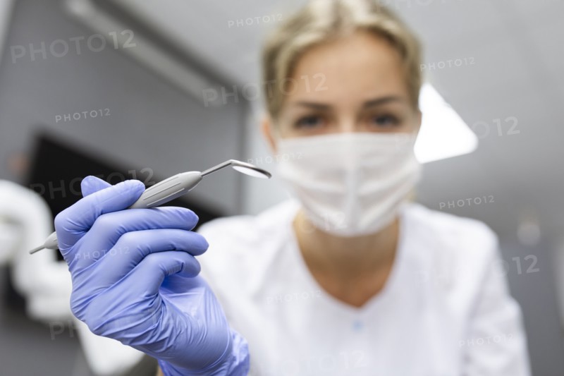 Patient point of view of dental assistant holding dental equipment