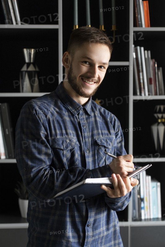 Smiling young businessman writing in note pad