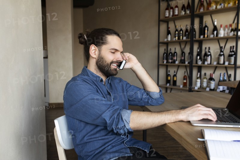 Young businessman on phone by laptop