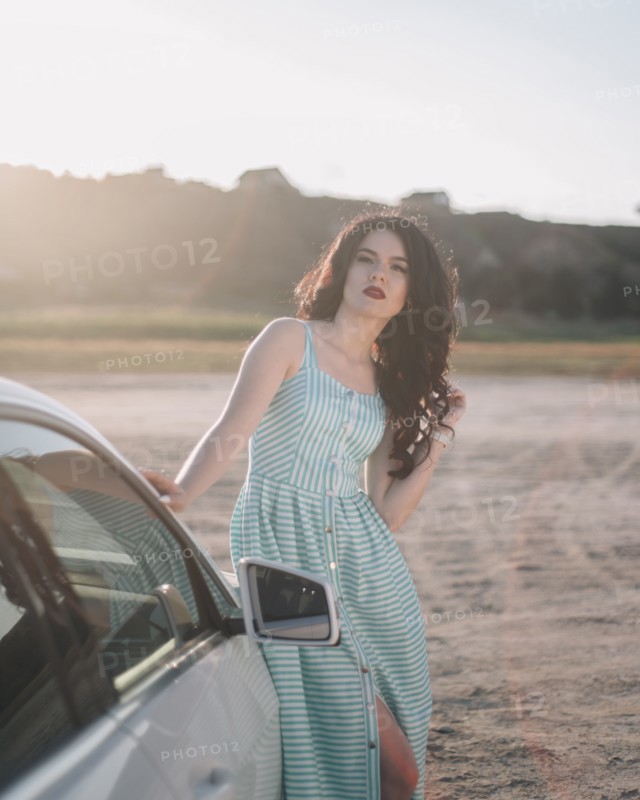 Young woman wearing striped dress by car