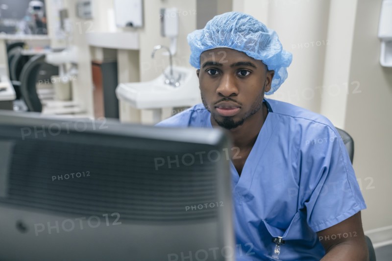Nurse wearing hair net using computer in hospital