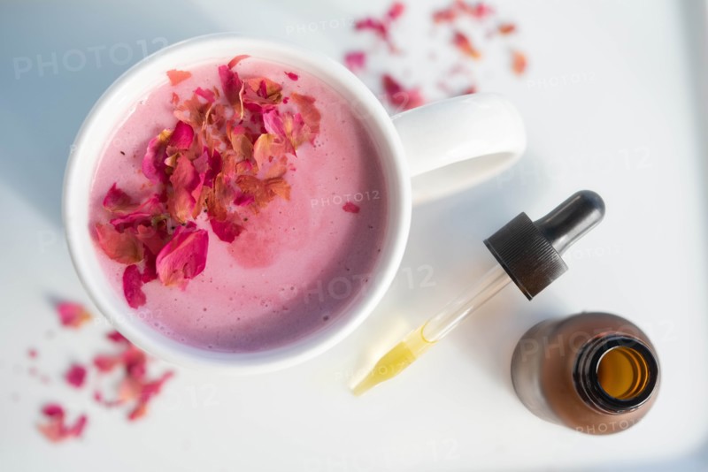 Pink drink topped with petals by pipette
