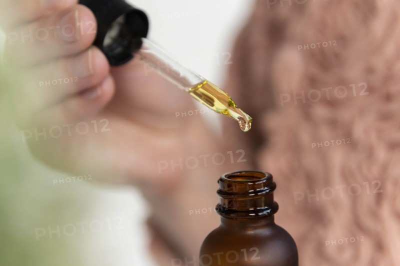 Hand of woman holding pipette of beauty oil