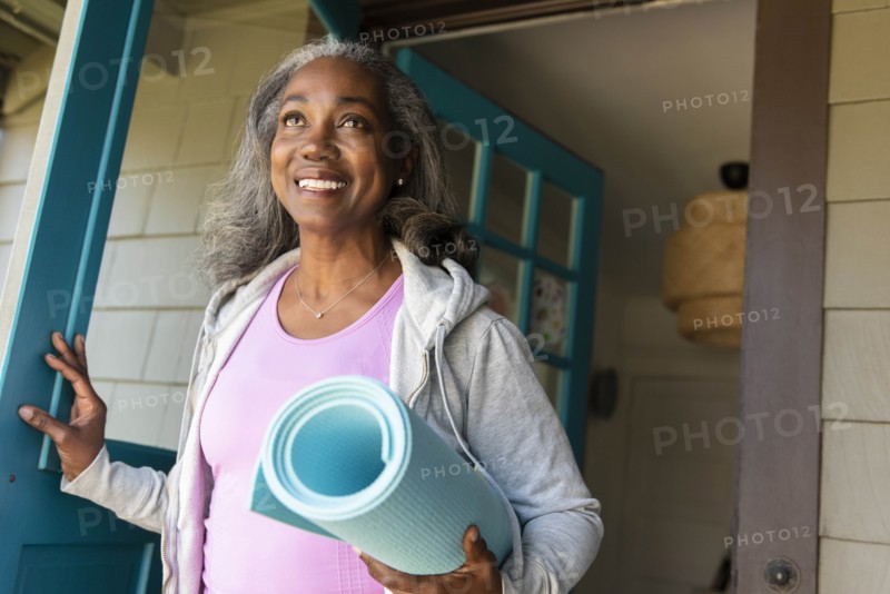 Smiling woman with yoga mat front door