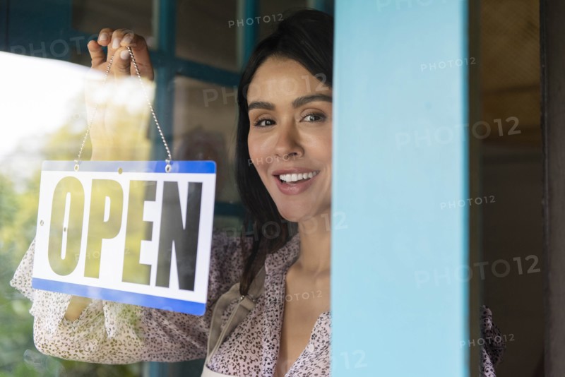 Woman turning open sign in shop window