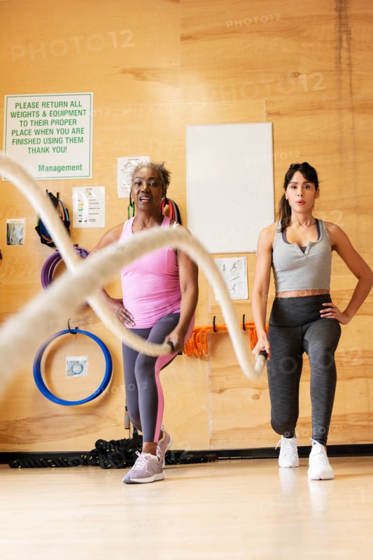 Women exercising with battle ropes in gym
