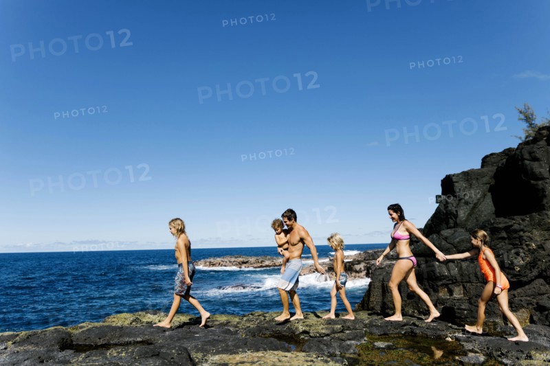Family walking on rocks by sea