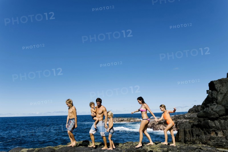 Family walking on rocks by sea