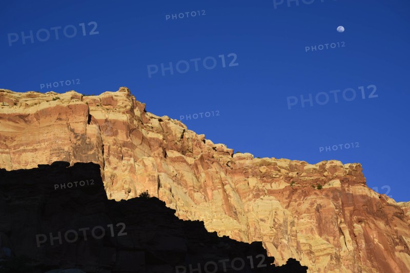 Moon over cliff in shadow in Capitol Reef National Park, USA