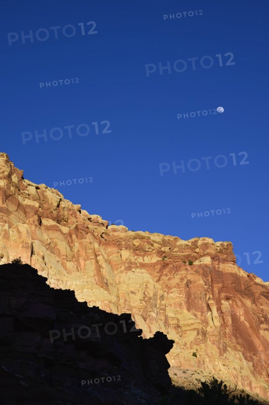 Moon over cliff in shadow in Capitol Reef National Park, USA