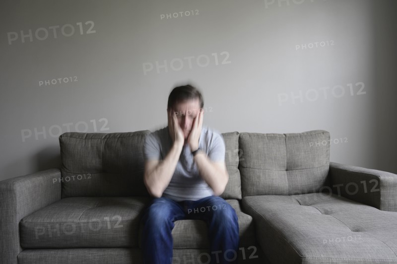 Depressed mature man sitting on couch