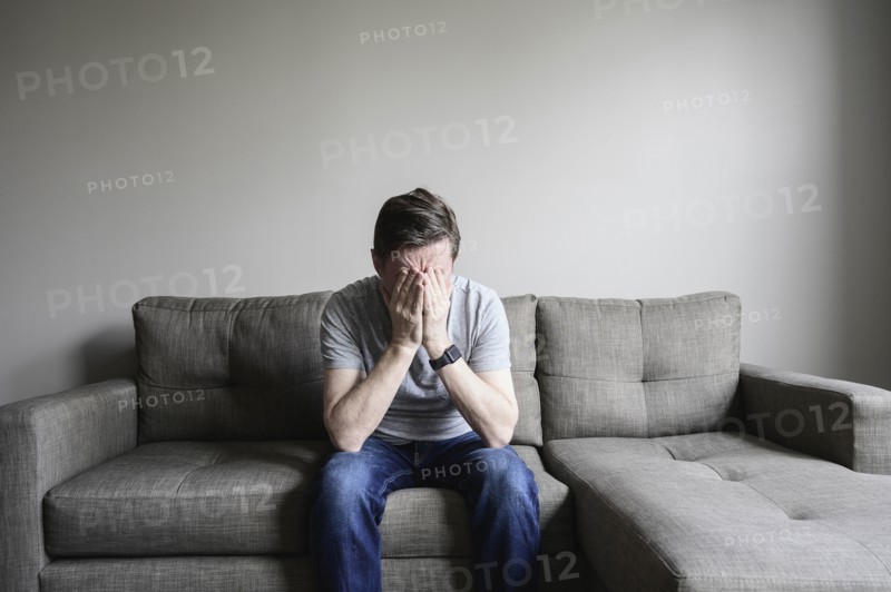 Depressed mature man sitting on couch