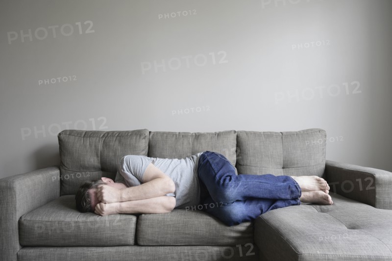 Depressed mature man lying on sofa