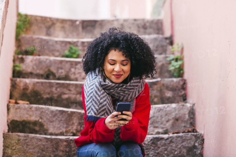 Young woman with smart phone sitting on steps