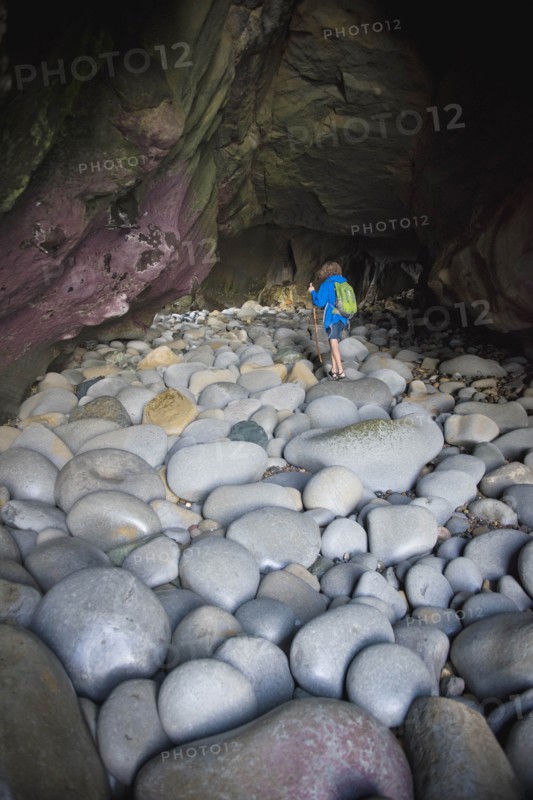 Teenage boy exploring cave with rocks in La Jolla, California