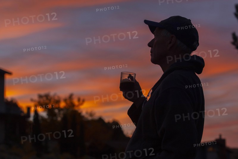 Silhouette of man holding coffee cup at sunset