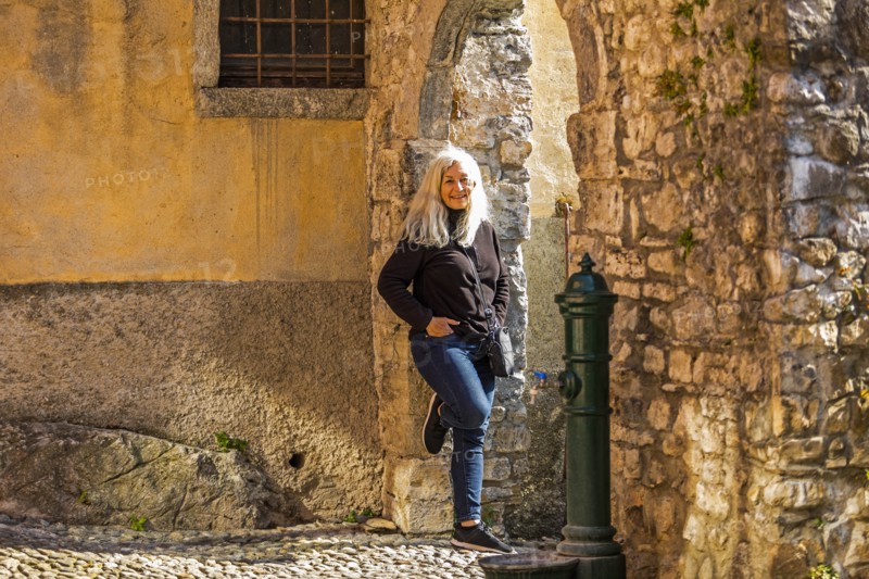 Mature woman leaning on stone arch in Lake Como, Italy