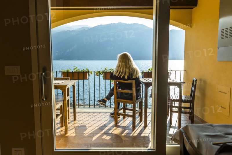 Mature woman sitting on balcony by Lake Como in Lombardy, Italy