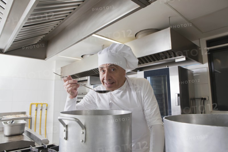 Smiling chef tasting food from pot
