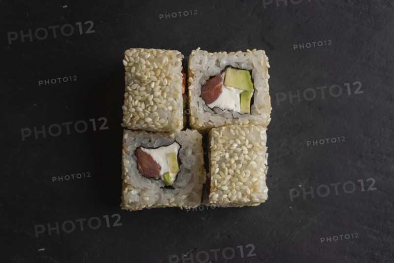 Sushi with sesame seeds on black surface