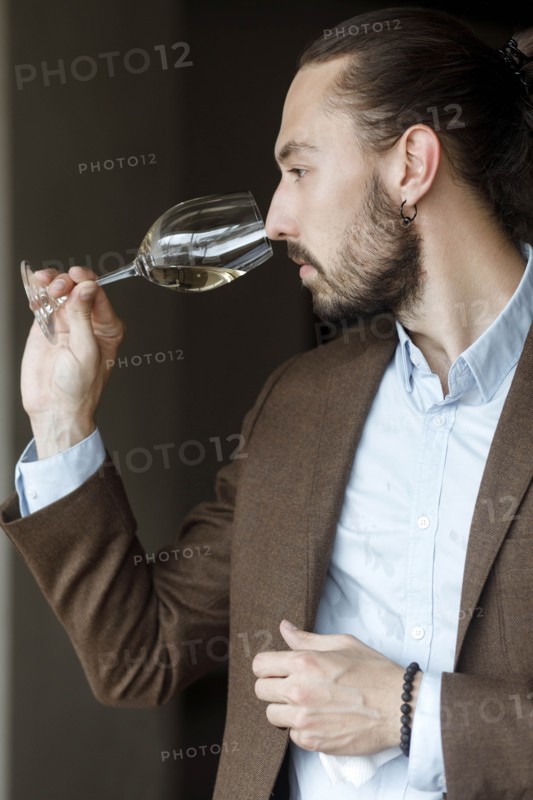 Young man smelling wine in glass at tasting