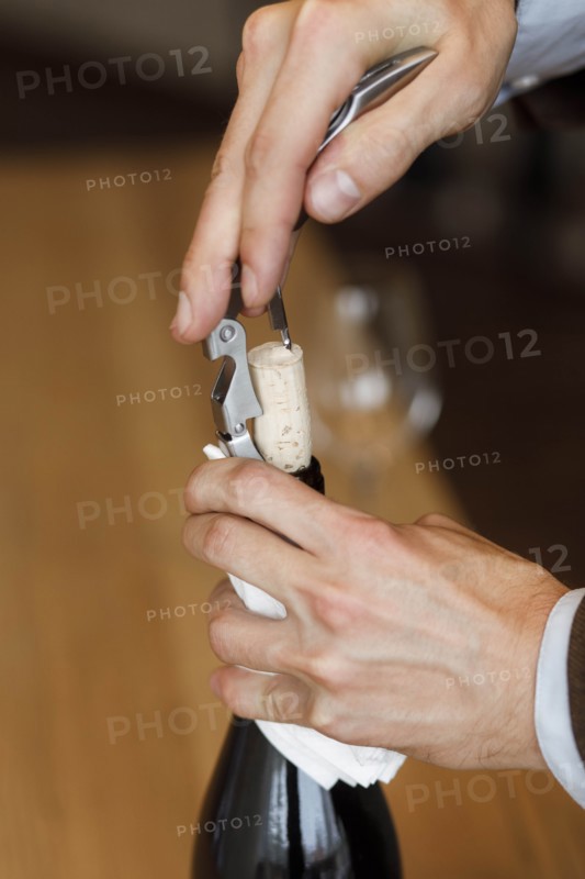 Hands of man opening bottle of wine