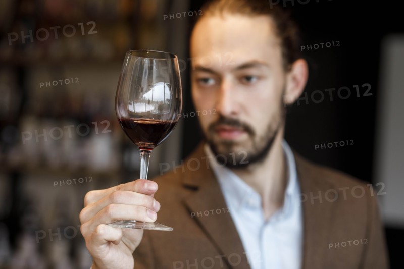 Young man examining glass of wine