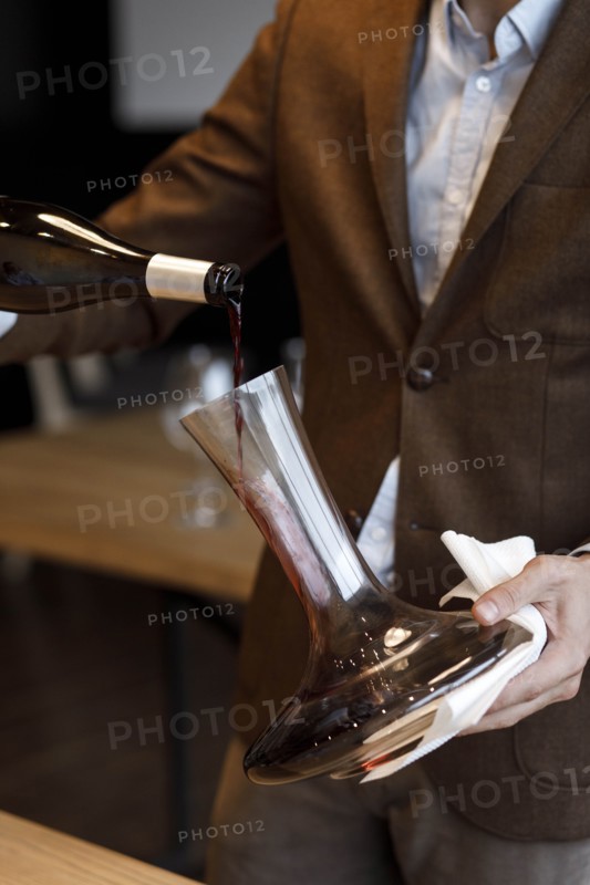 Waiter pouring red wine into decanter