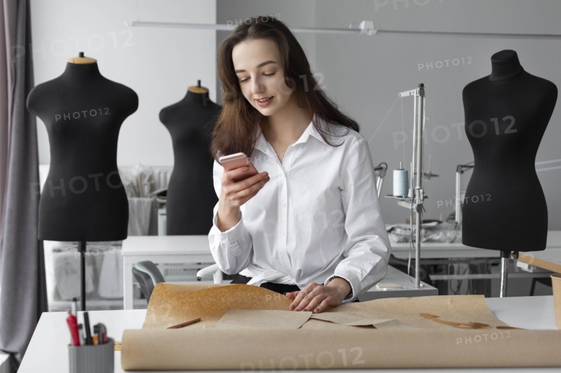 Fashion designer using smartphone in studio