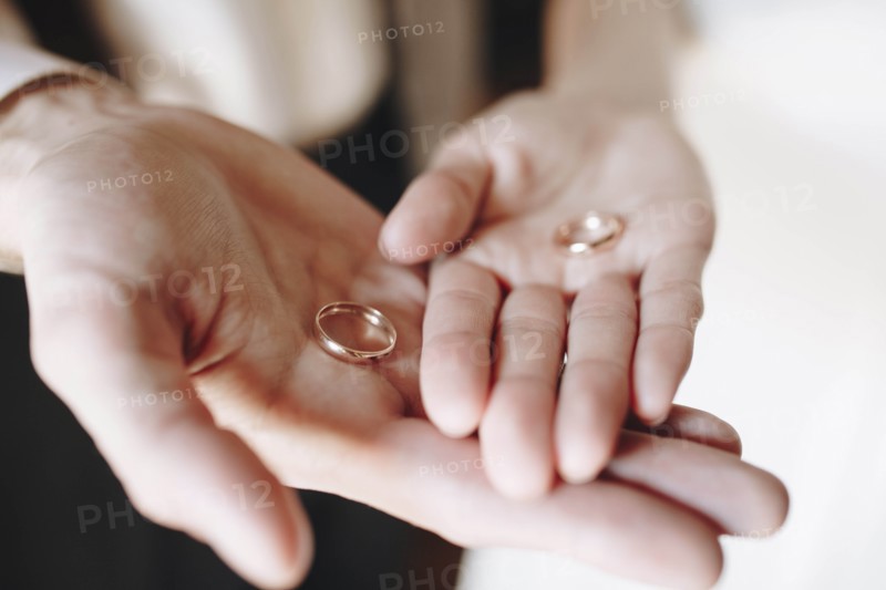 Hands of young couple holding wedding rings