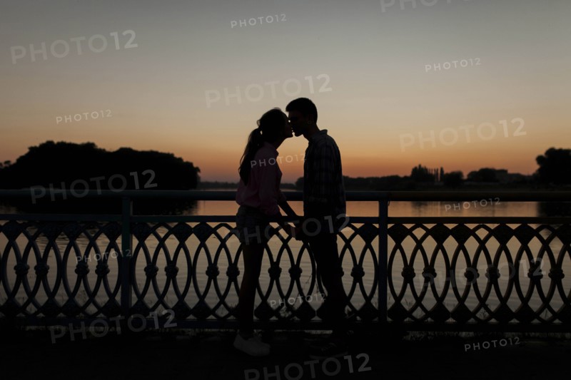 Silhouettes of young couple kissing at sunset