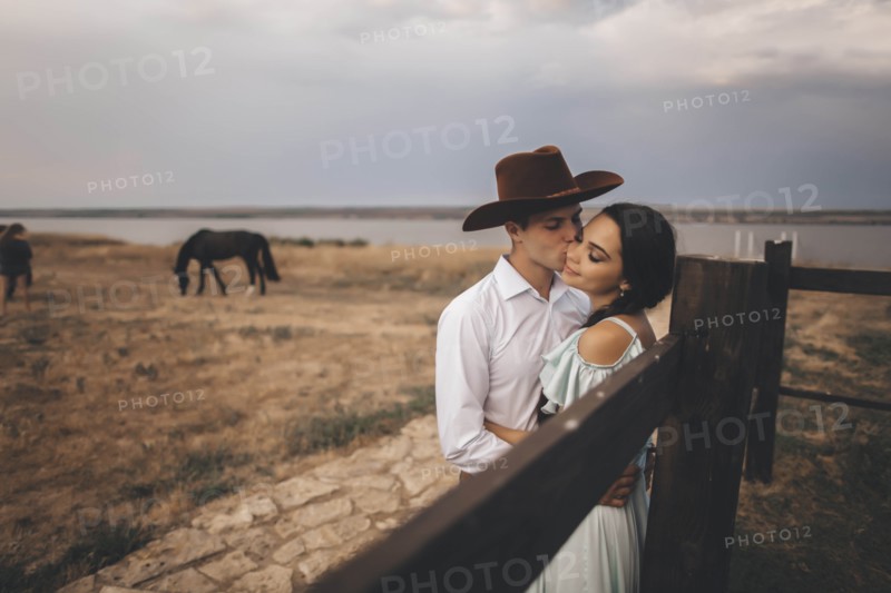 Young couple embracing in field by horses