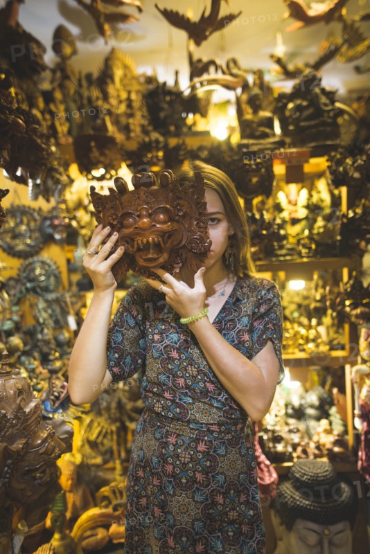 Young woman holding Barong mask in store in Bali, Indonesia