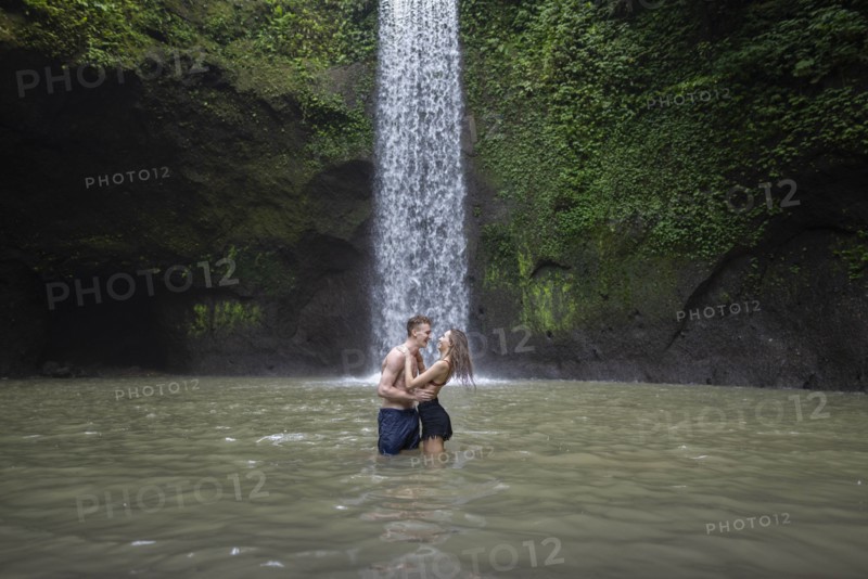 Young couple embracing in river by Tibumana Waterfall in Bali, Indonesia