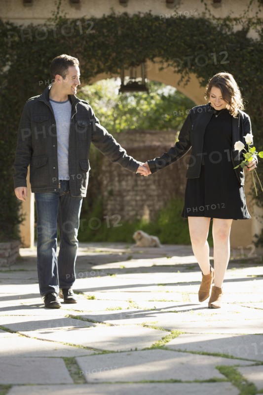 Young couple holding hands by arch