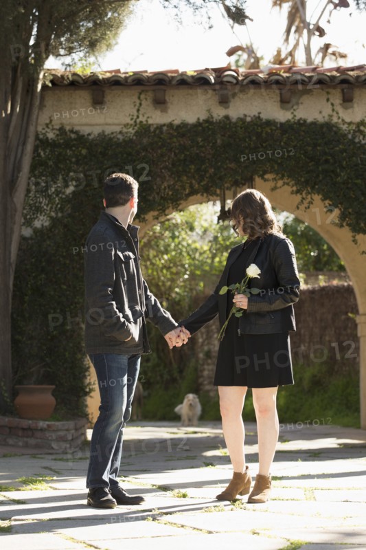 Young couple holding hands by arch