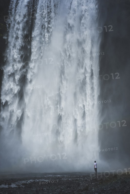 Man standing by Skogafoss waterfall in Iceland