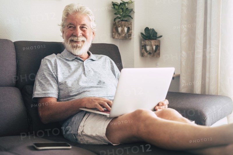 Smiling senior man using laptop on sofa