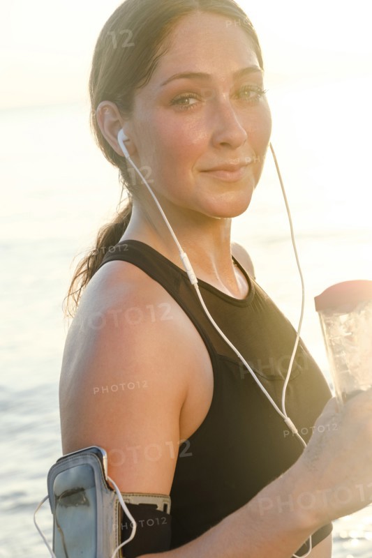 Woman wearing headphones holding water bottle