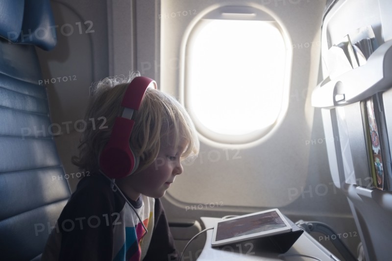 Boy watching digital tablet on airplane