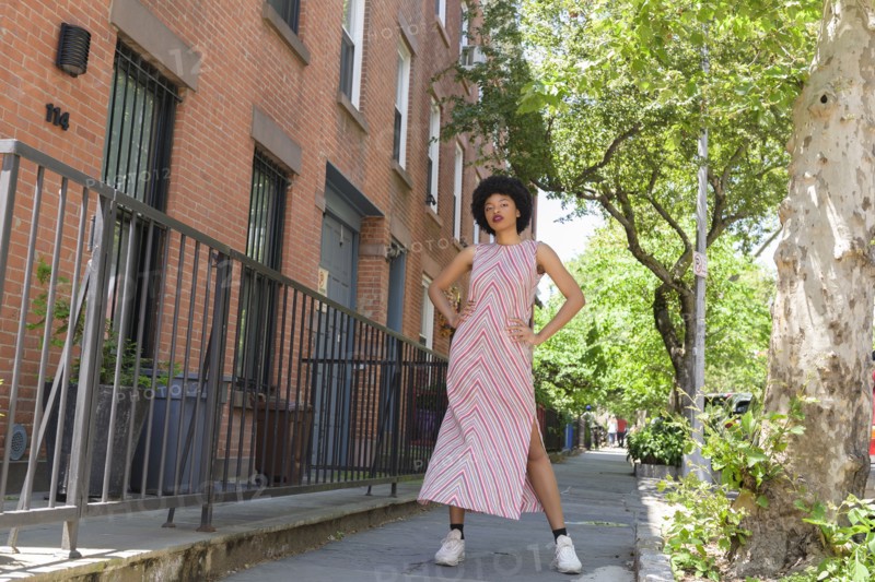 Woman wearing striped dress by brick townhouses