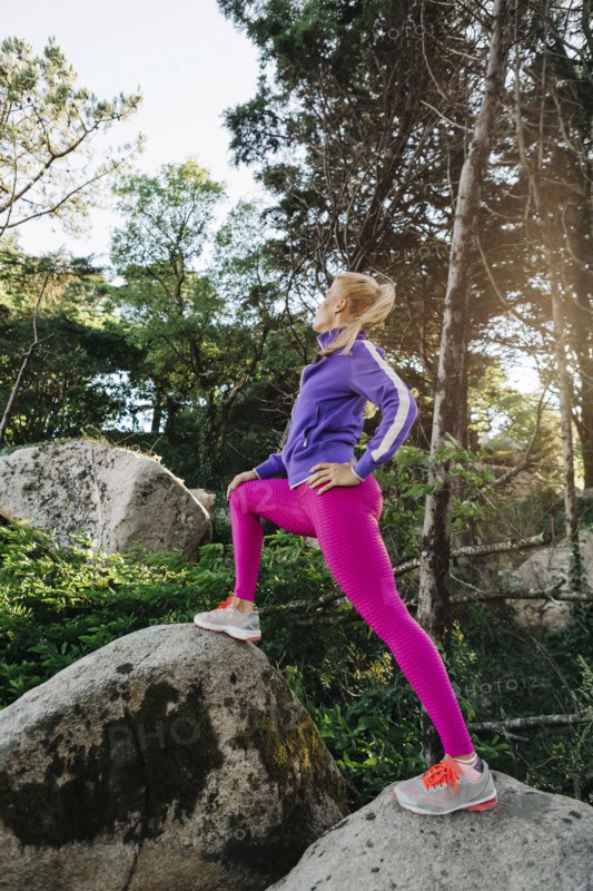 Woman wearing sportswear on rocks in forest