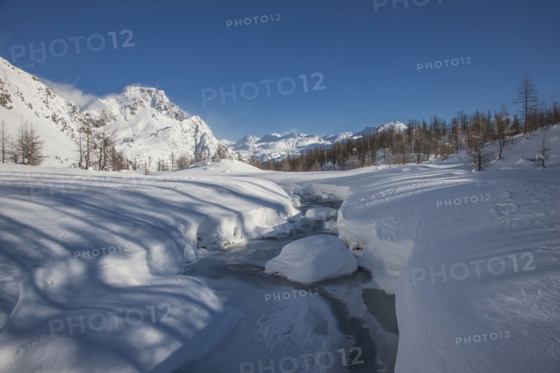 Frozen river in snow covered mountainous landscape in Alpe Devero, Italy