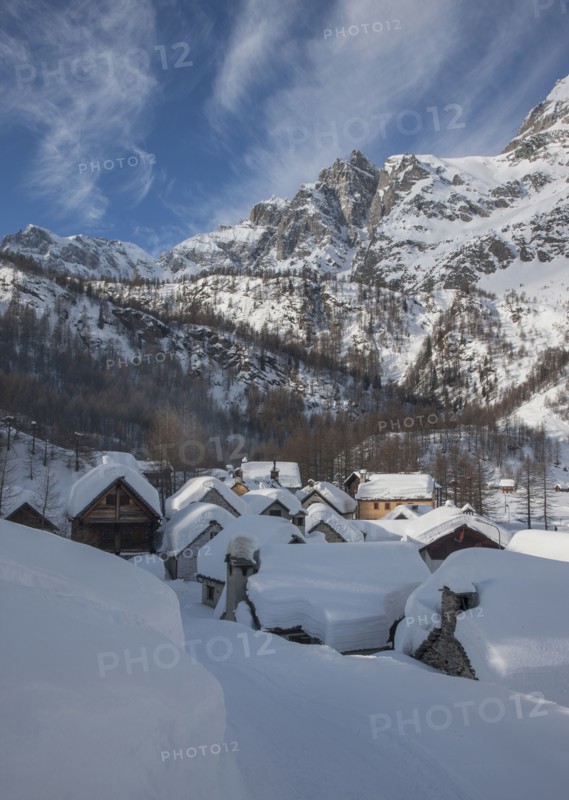 Snow covered village by mountain in Alpe Devero, Italy