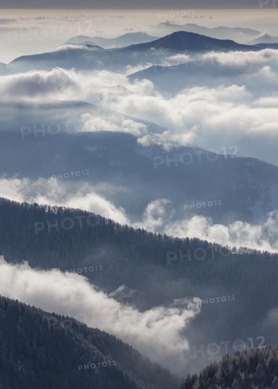 Fog over forest covered mountains in Piedmont, Italy