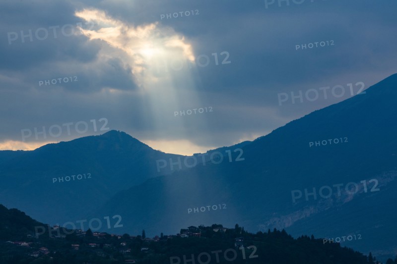 Sunbeams through clouds over mountains in Lombardy, Italy